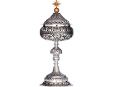 Silver ciborium with elements in relief and golden Cross